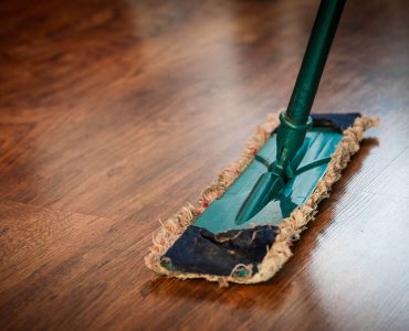 a mop on a wooden floor with a green handle
