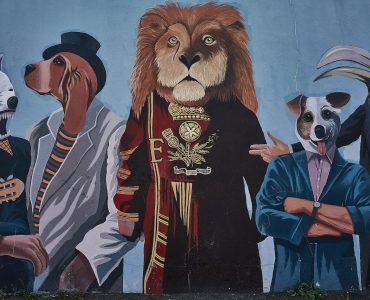 a painting of a group of people and dogs on a wall