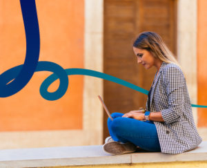 a woman sitting on a ledge using a laptop computer