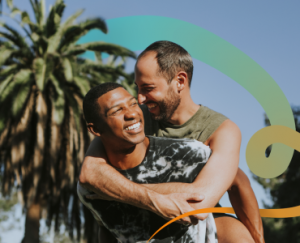 a couple of men hugging each other in front of a palm tree