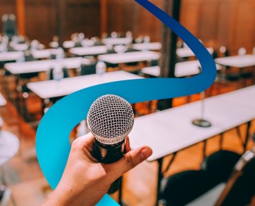 a person holding a microphone in front of a room full of tables