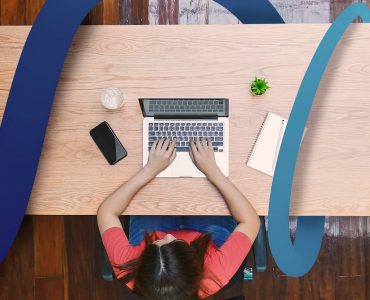 a woman sitting at a desk typing on a laptop