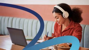 a woman sitting at a table with a laptop and headphones on